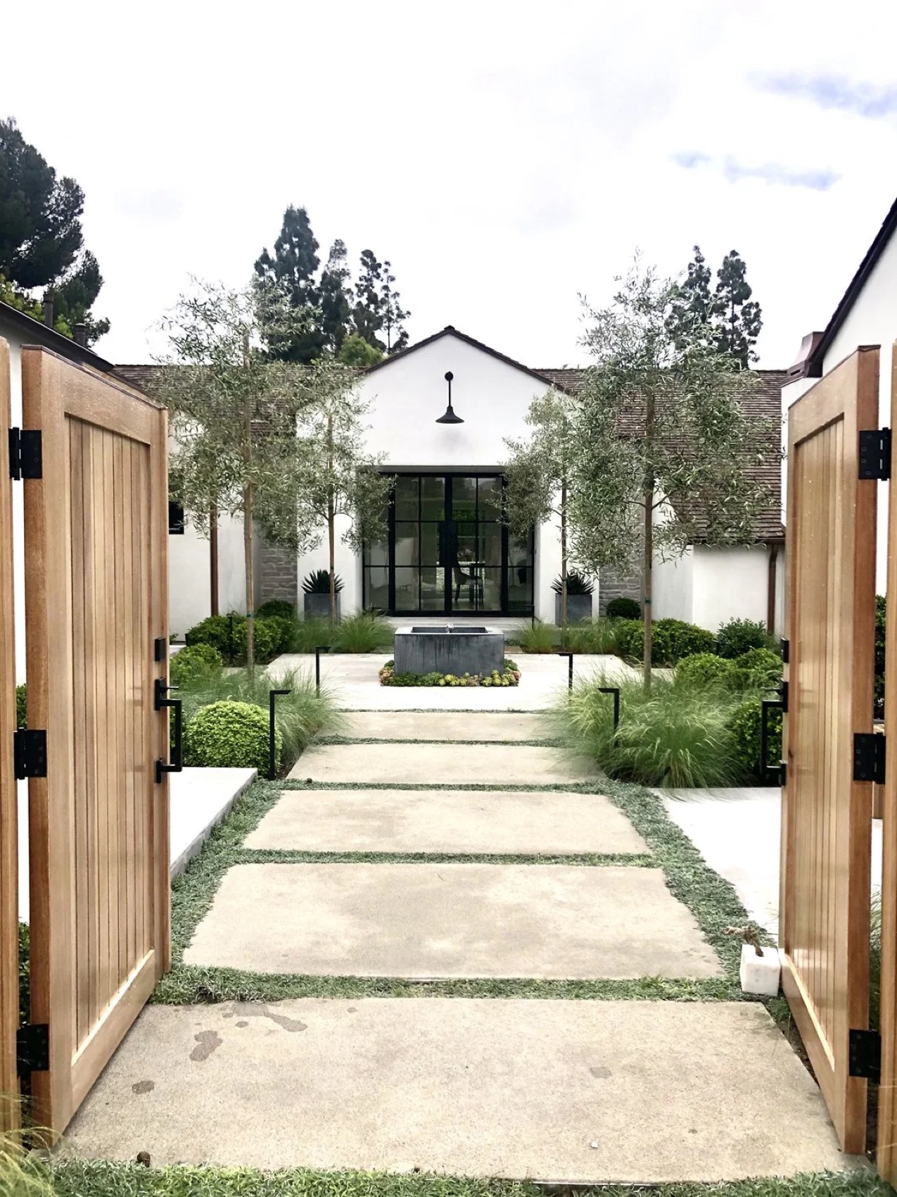 Architectural entrance with landscaped courtyard and natural materials by KADI Design