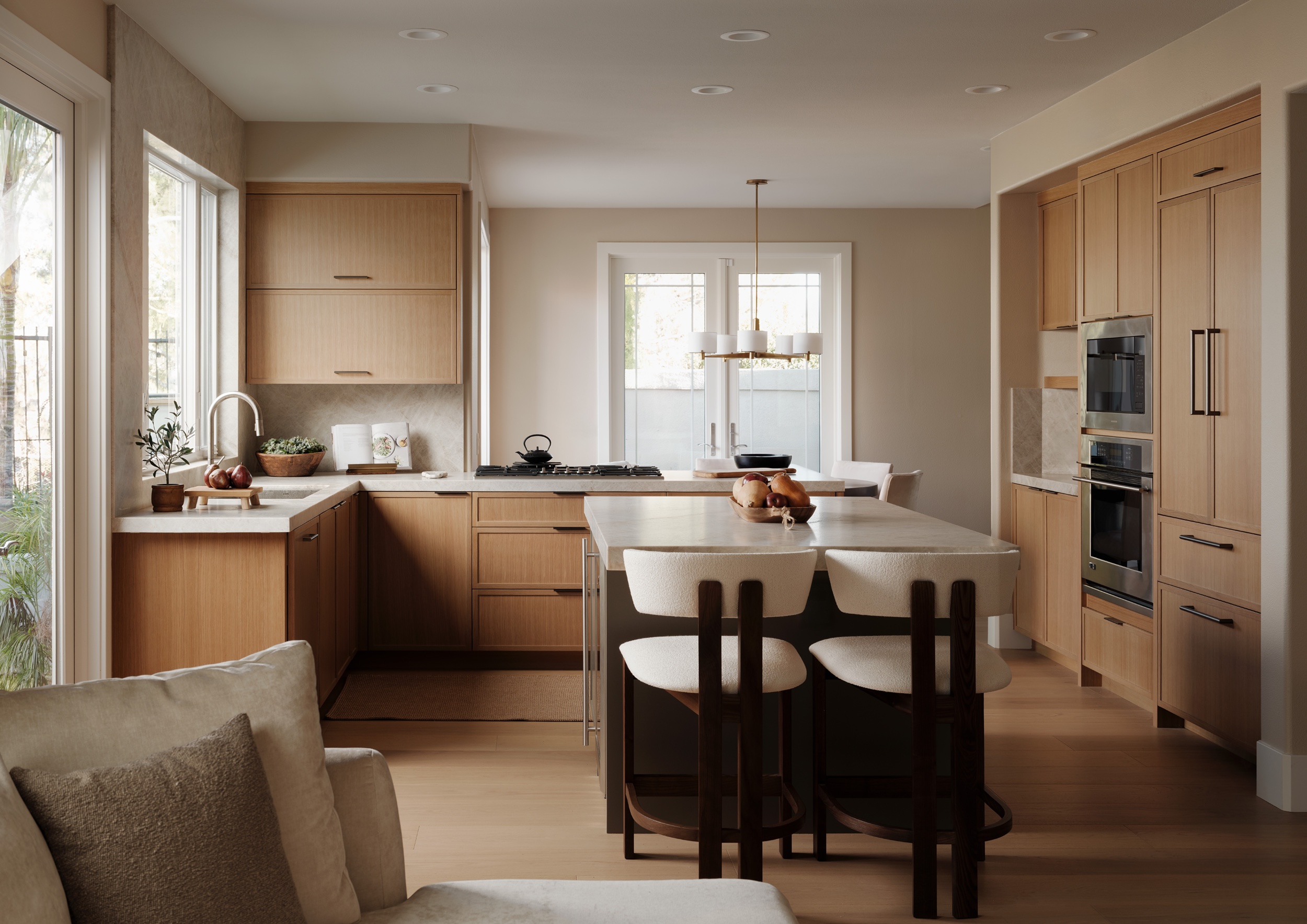 Light-filled Newport Beach kitchen interior designed by KADI Design with white oak cabinetry and a natural stone island